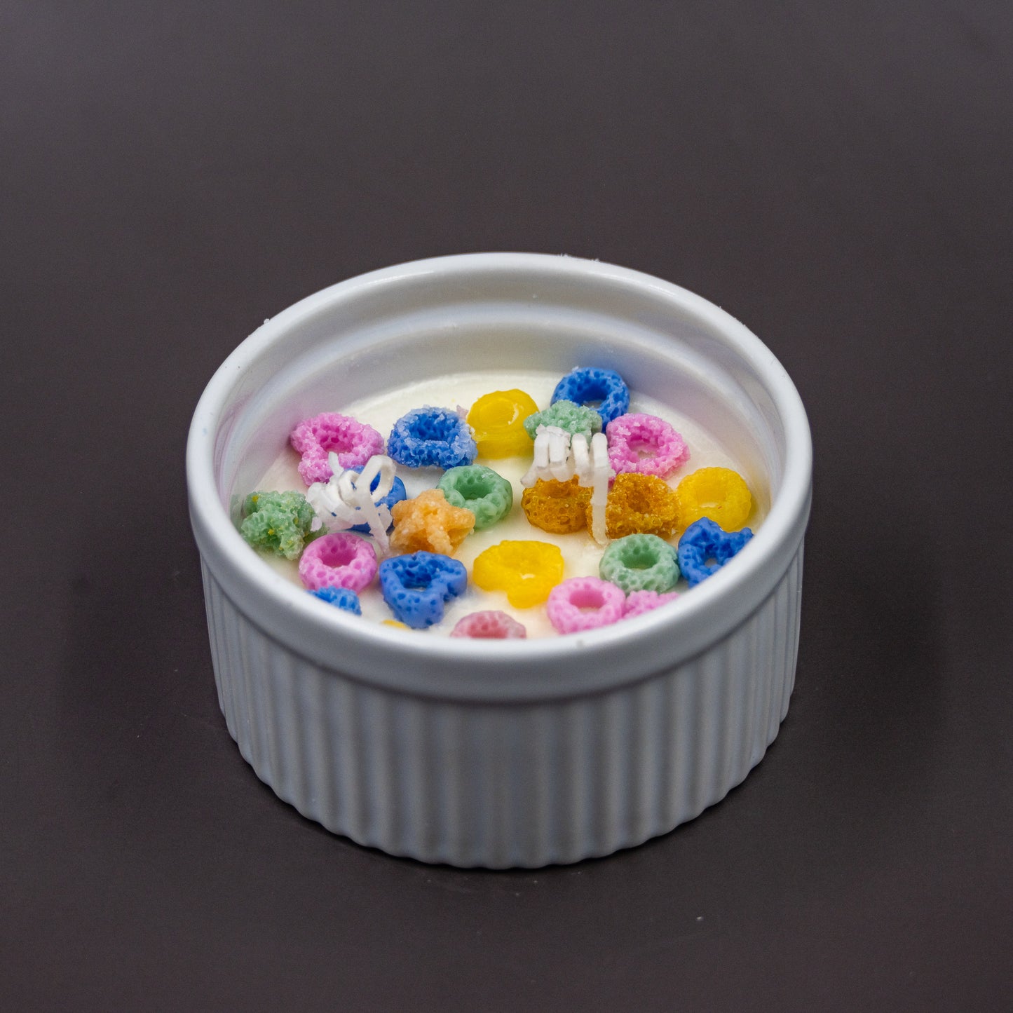 This handcrafted cereal candle is a whimsical home decor piece that perfectly mimics a bowl of colorful fruit loops cereal floating in white milk, providing a delightful, nostalgic aroma of the classic breakfast treat. It's a fun, foodie item designed to evoke happy childhood memories. 
