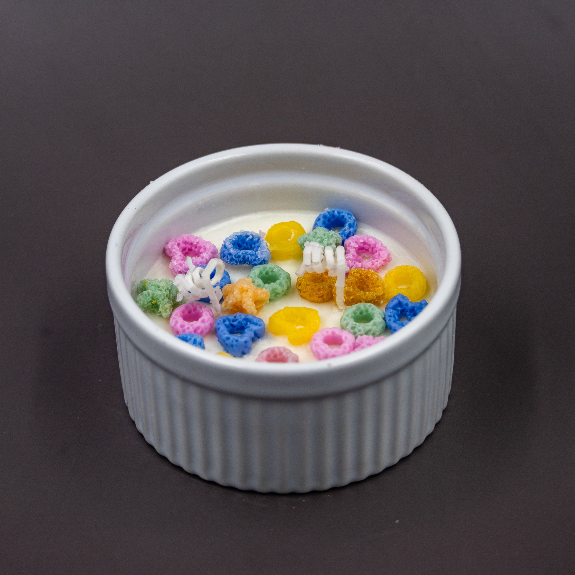 This handcrafted cereal candle is a whimsical home decor piece that perfectly mimics a bowl of colorful fruit loops cereal floating in white milk, providing a delightful, nostalgic aroma of the classic breakfast treat. It's a fun, foodie item designed to evoke happy childhood memories. 