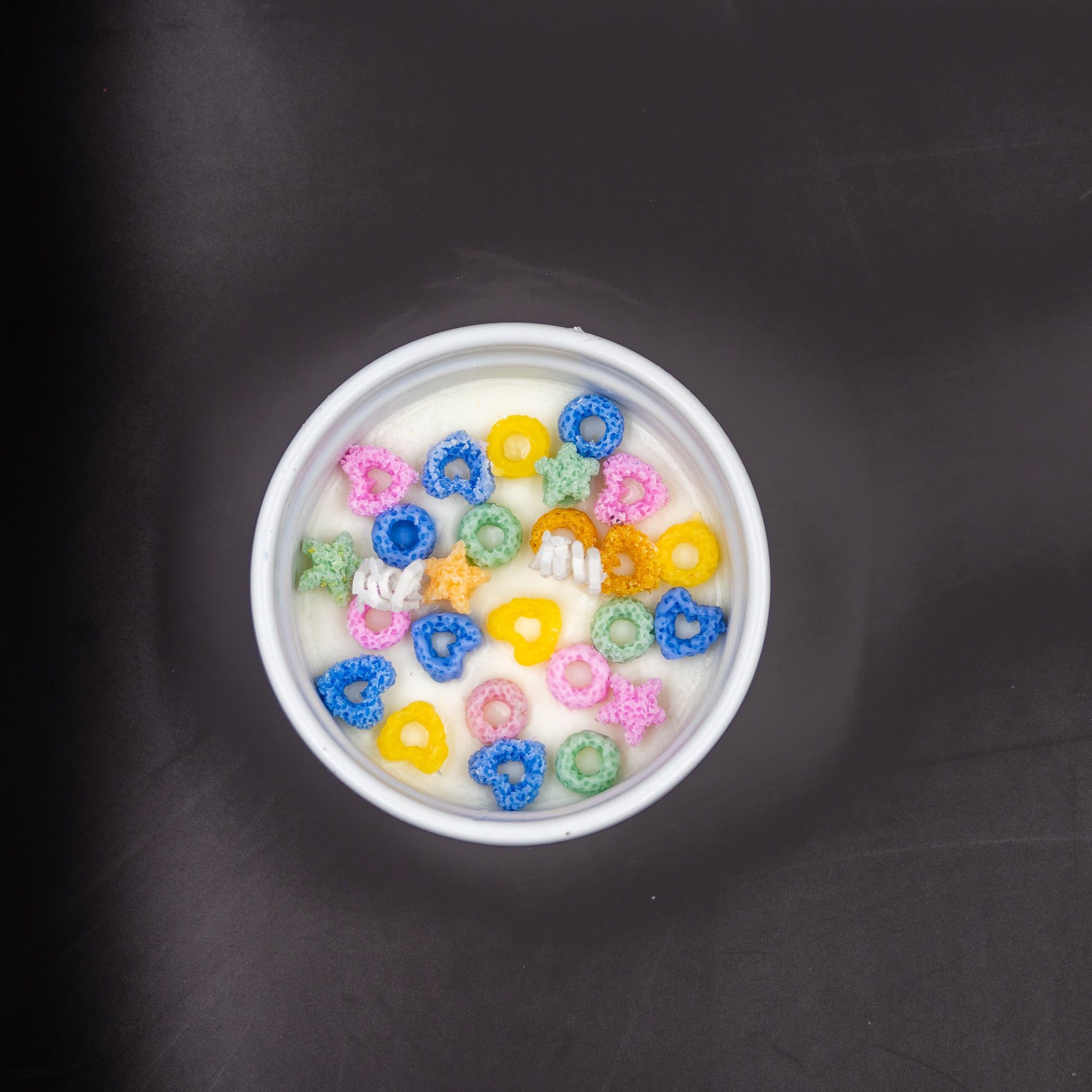 This handcrafted cereal candle is a whimsical home decor piece that perfectly mimics a bowl of colorful fruit loops cereal floating in white milk, providing a delightful, nostalgic aroma of the classic breakfast treat. It's a fun, foodie item designed to evoke happy childhood memories. 