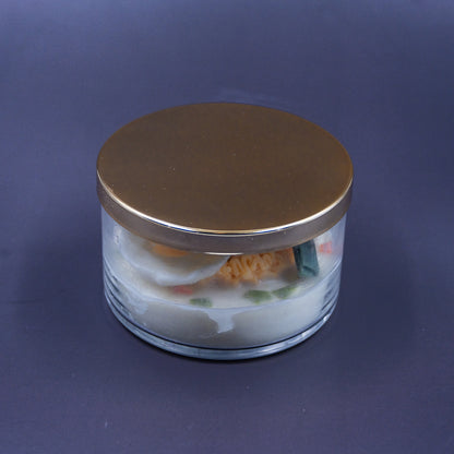This highly realistic, handcrafted candle is a culinary work of art, designed to perfectly mimic a bowl of ramen noodles with a poached egg, kelp knot, carrots, and other vegetable toppings, all in a white savory bone broth base. Primarily made from a blend of natural soy and beeswax, this unique item is an ideal novelty decor piece. The entire assembly is presented in a glass jar with rose golden lid.